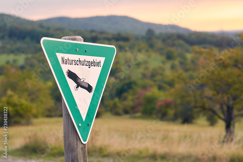 Schild Naturschutzgebiet vor einer Landschaft im Grünen photo