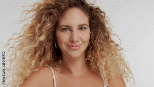 happy smiling young natural model in studio with blonde curly hair moving blowing streaming in air