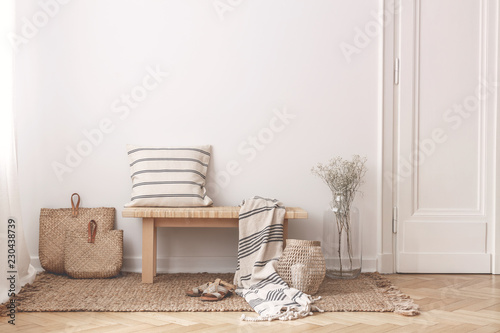 Two bags made of straw next to wooden table with striped pillow and a blanket on it photo