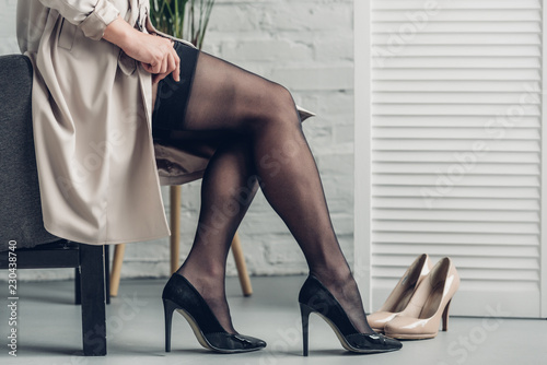 cropped shot of trans man in trench coat putting on stockings