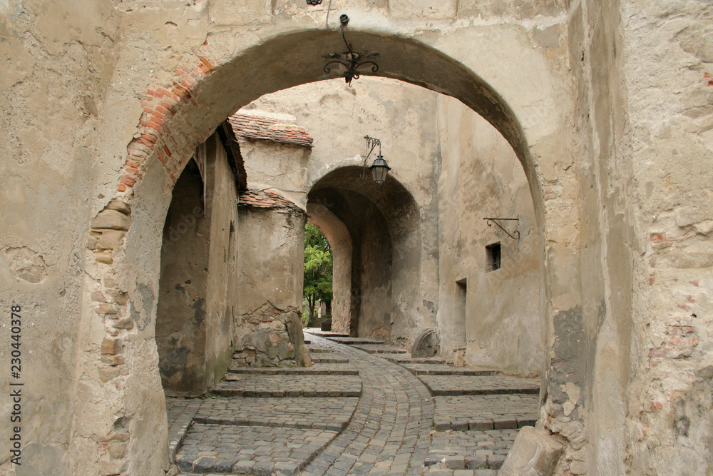 Old buildings in Sighisoara, Romania. Details of Romanian architecture, walls and gates. Classic stone street.
