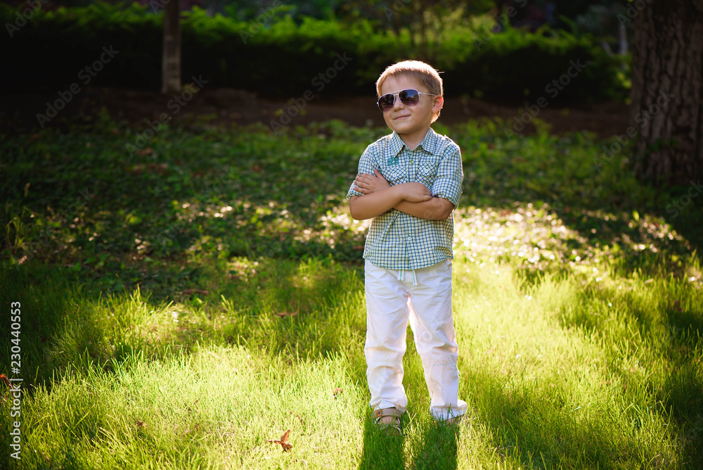 Happy little boy with sunglasses in the garden.