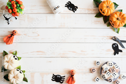 Top view of white and yellow ghost pumpkins with bat spider mummy jelly worm and gift box on white wooden background. halloween concept.