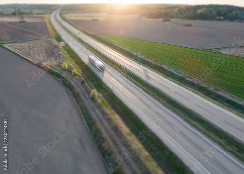 Obraz na plátně Aerial view of motion blurred truck on highway against sunset with tilt-shift ef