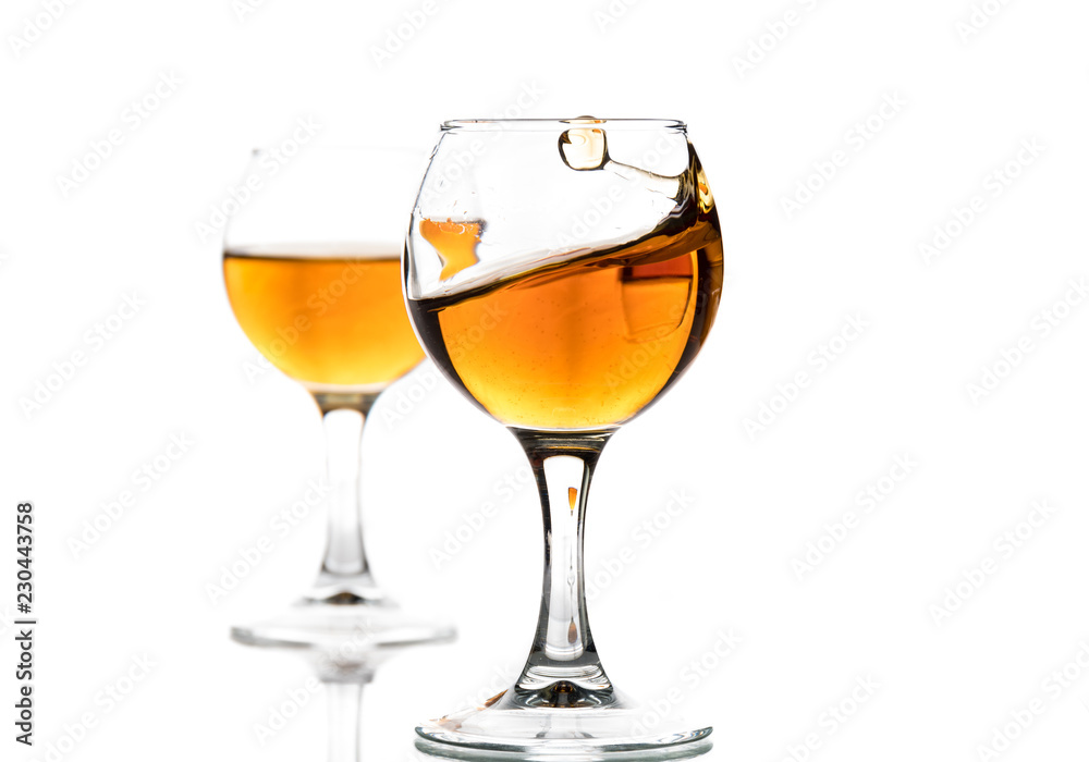 A round glass with brandy and a splash of drink inside