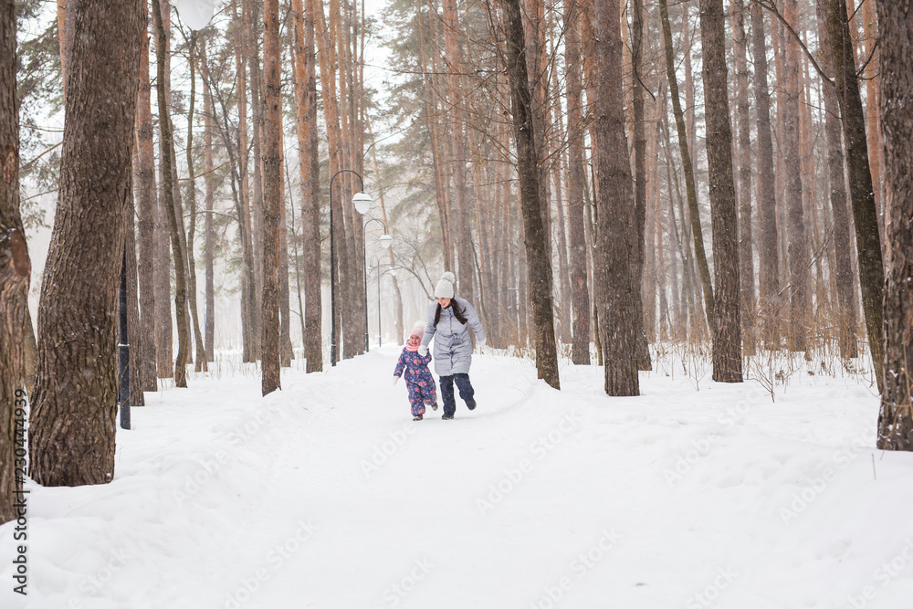 Family, children and nature concept - Mother with daughter have fun in the winter park