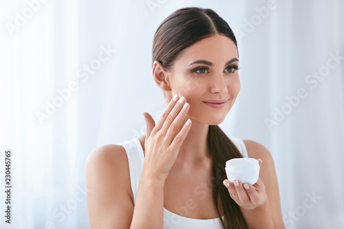 Beauty. Beautiful Woman Applying Face Cream On Soft Facial Skin