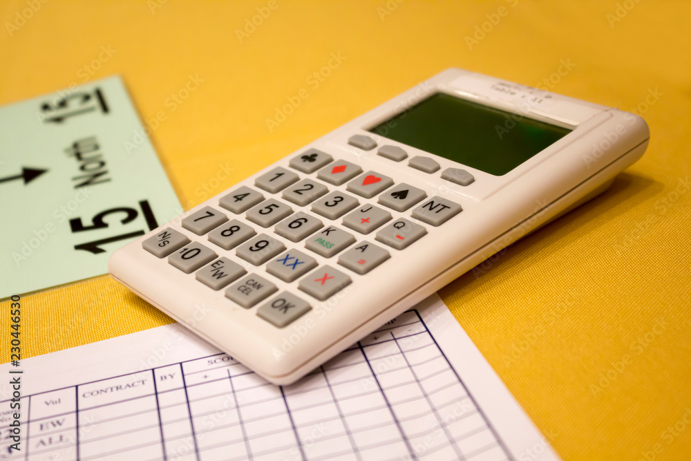 Сalculator and information sheets for the bridge game on the table with yellow tablecloth Сalculator and information sheets for the bridge game on the table with yellow tablecloth