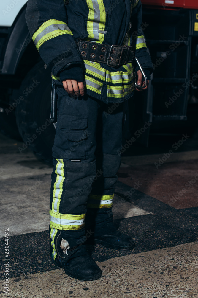 partial view of firefighter in protective fireproof uniform standing at fire department