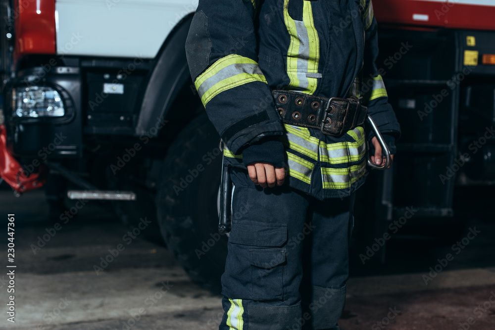partial view of firefighter in protective fireproof uniform standing at fire department partial view of firefighter in protective fireproof uniform standing at fire department