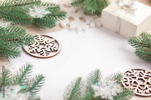 Christmas composition. Christmas gift, wooden snowflakes and figurines, pine cones, fir branches on wooden white ba