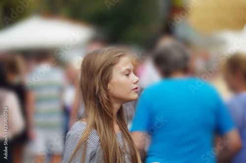 Portrait of a teenage girl on a background of people in a big city. loneliness among people