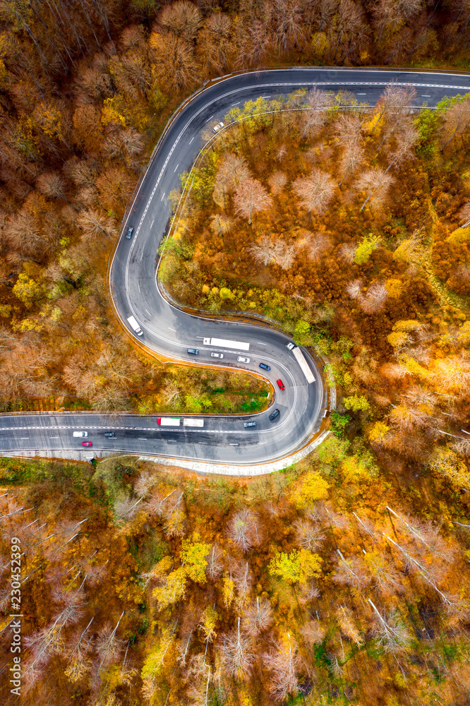 Winding curved road with cars and trucks on the road. Aerial view.