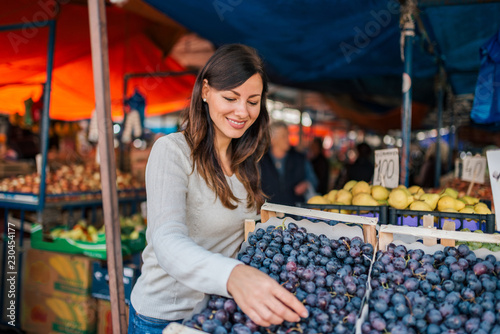 Smiling woman buying fresh grapes.