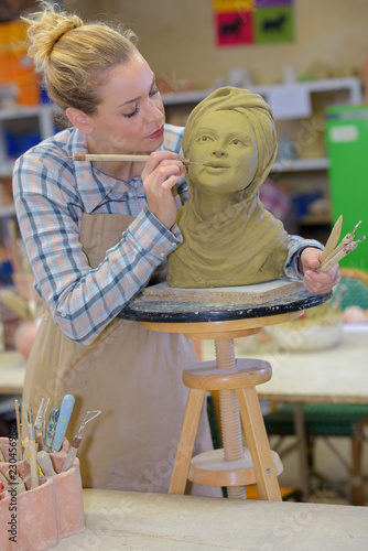 woman decorating head in pottery class