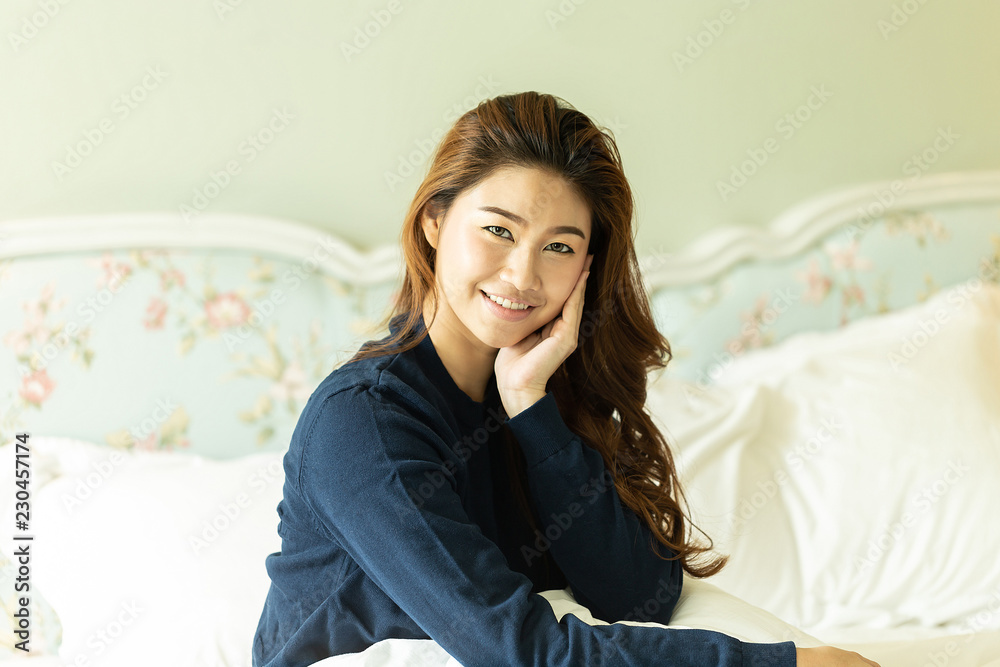 Beautiful Attractive Asian woman wearing blue sweater sitting on bed and smile with healthy skin feeling so fresh and happiness Beautiful Attractive Asian woman wearing blue sweater sitting on bed and smile with healthy skin feeling so fresh and happiness