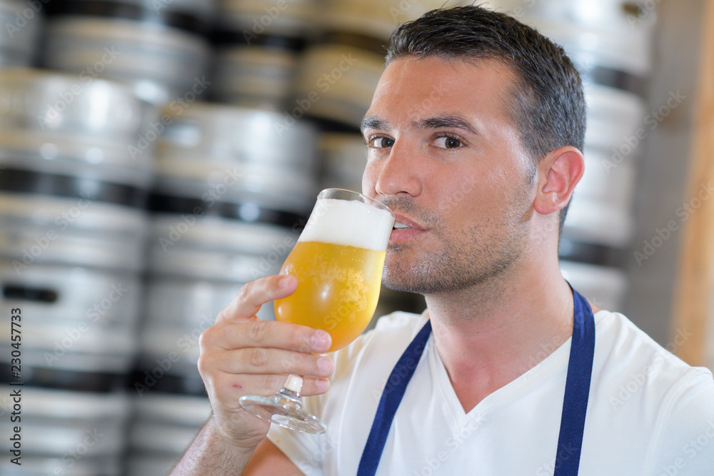 handsome brewer in uniform tasting beer at the brewery handsome brewer in uniform tasting beer at the brewery