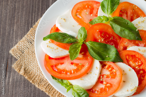 Close-up photo of caprese salad with ripe tomatoes  basil  buffalo mozzarella cheese. Italian and Mediterranean food concept. Fresh and healthy organic meal. Starter and antipasti. 