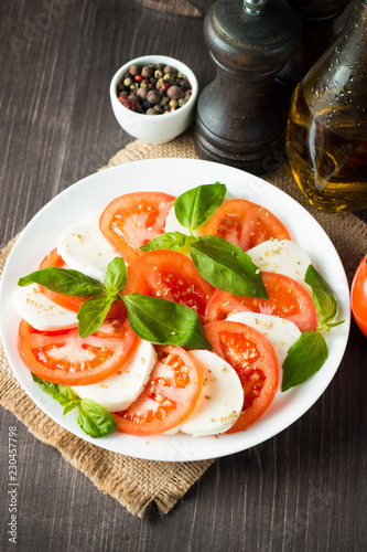 Close-up photo of caprese salad with ripe tomatoes, basil, buffalo mozzarella cheese. Italian and Mediterranean food concept. Fresh and healthy organic meal. Starter and antipasti. 