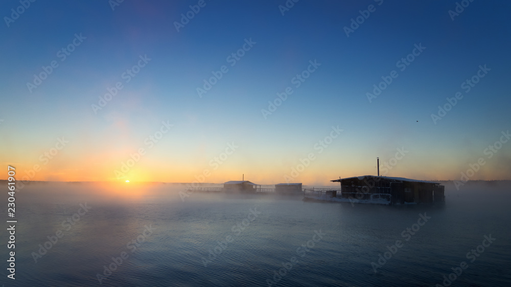 зимние рыбацкие домики на озере холодным туманным утром, Россия Урал  