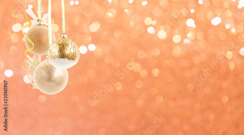Hanging golden christmas balls with riboons on pink bokeh background photo