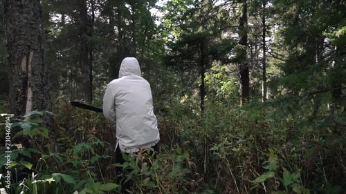 Man with machete in campaign through impassable areas of forest. Footage. Single journey in wild. Concept of man makes his way through difficulties and obstacles photo