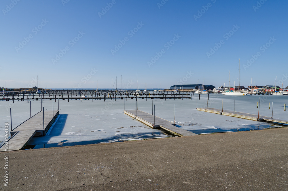 Marina in winter with frozen water and a few boats