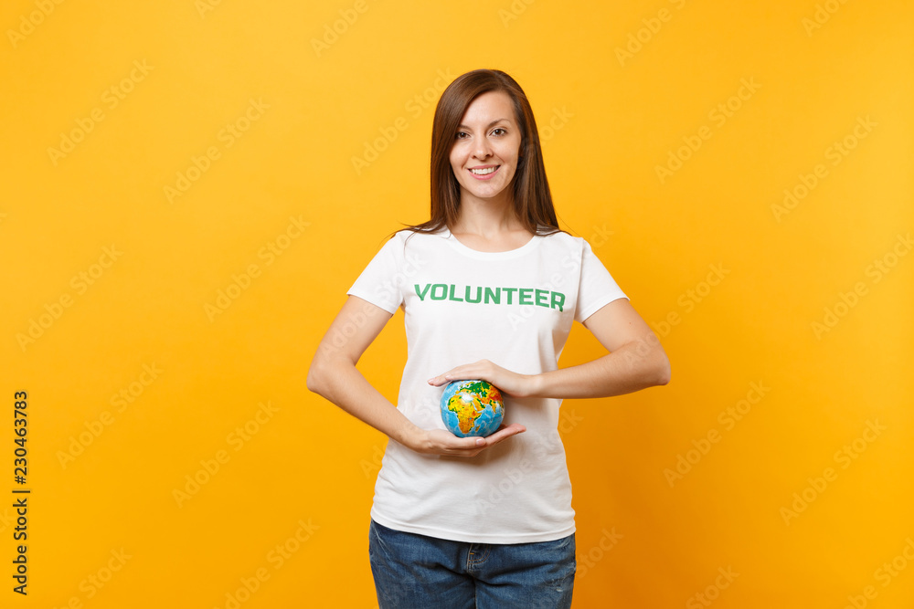 Portrait of woman in white t-shirt with written inscription green title volunteer hold in palms Earth world globe isolated on yellow background. Voluntary free assistance help, charity grace concept. Portrait of woman in white t-shirt with written inscription green title volunteer hold in palms Earth world globe isolated on yellow background. Voluntary free assistance help, charity grace concept.