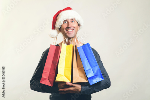 Happy man shopping christmas gifts. Christmas shopping idea concept. Man in Santa hat. Shopping bags. Santa holding shopping bags. Christmas sales. New Year and Christmas. Santa helper hat with bags.