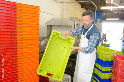 Factory worker holding plastic crate