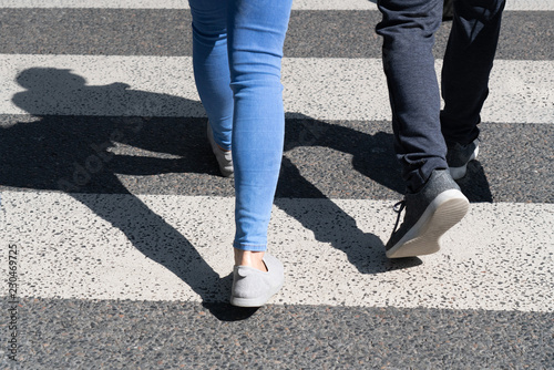 View of pedestrians legs crossing the white zebra crossing line