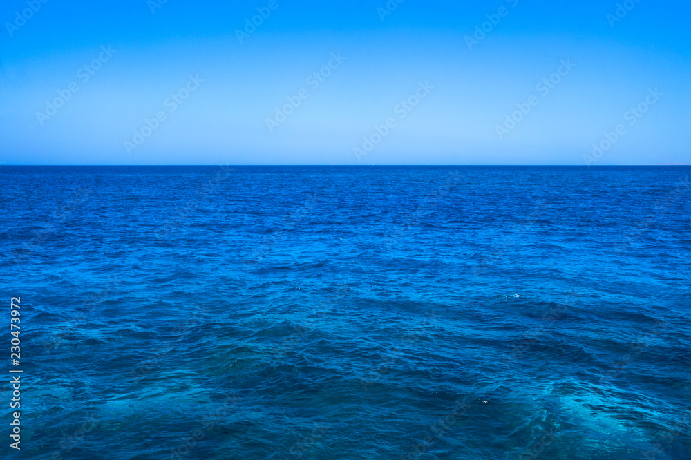 Beautiful blue sea surface with the sky. Oceanic deserted, lonely theme for background. Stock photo for tourist design