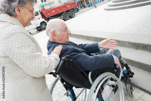 an old woman is pushing husband in wheelchair