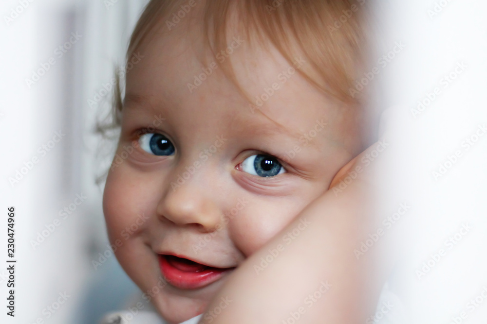 close-up portrait of a handsome little boy of one year old with blue eyes and blond hair