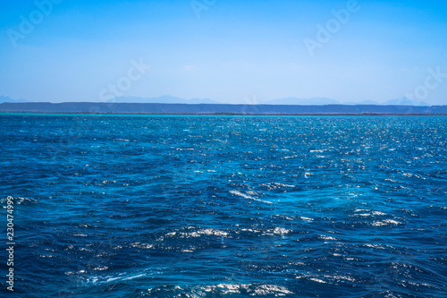 Beautiful blue sea surface with the sky. Oceanic deserted, lonely theme for background. Stock photo for tourist design