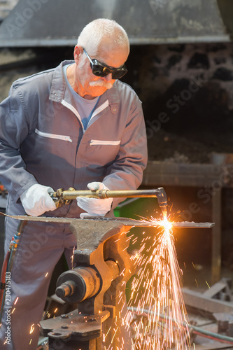 senior workman working with grinder producing flash of sparkles