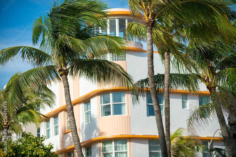 Palm trees blowing in front of classic Art Deco architecture in South Beach, Miami, Florida, USA