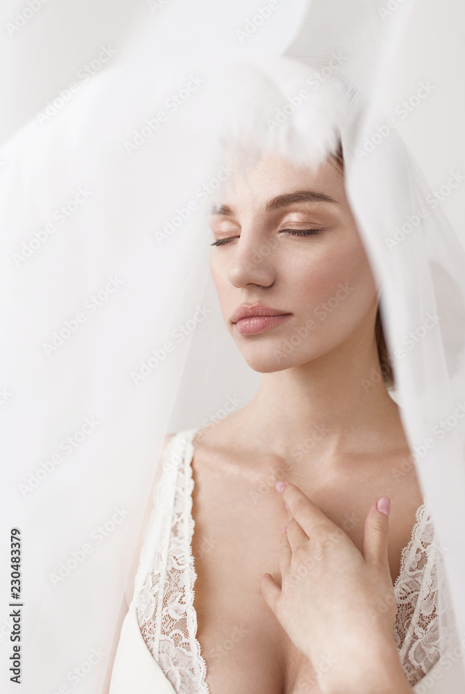 Bride's morning. Beautiful tender girl in white lace bra and white veil. Girl holding white fluffy feather. Fine art. Bride's morning. Beautiful tender girl in white lace bra and white veil. Girl holding white fluffy feather. Fine art.