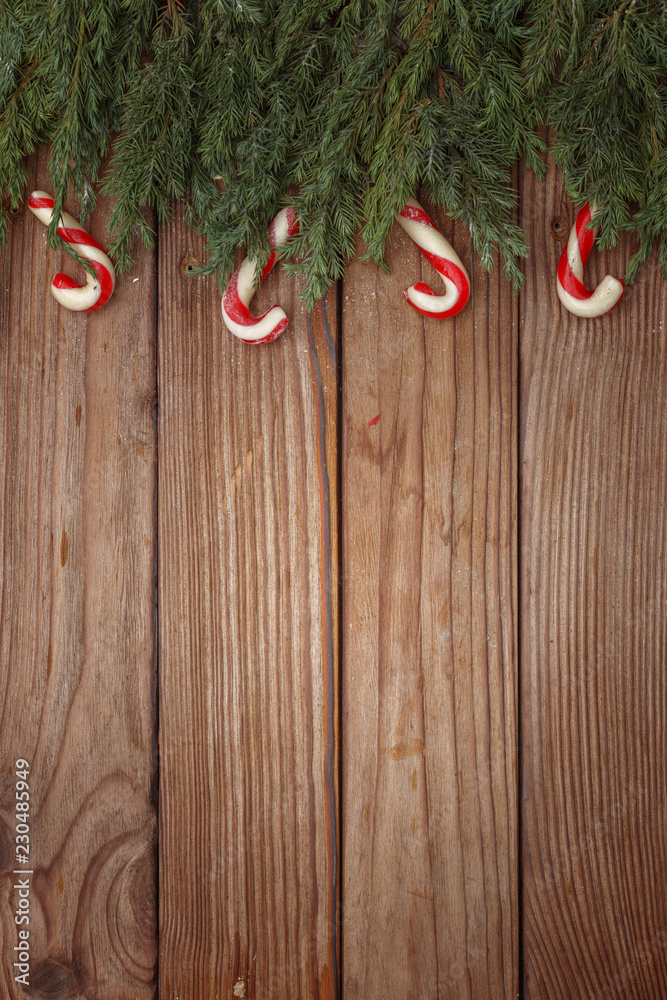 Christmas composition of tree branches, candies and decorations on wooden background. Top view. Copy space.