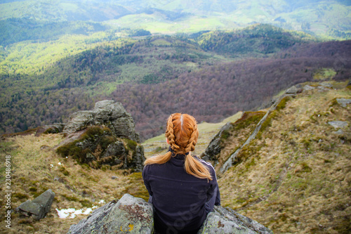 The girl sits on the edge of a cliff with a view of the mountains. Ukrainian Carpathian Mountains. Traveling © Yaroslav