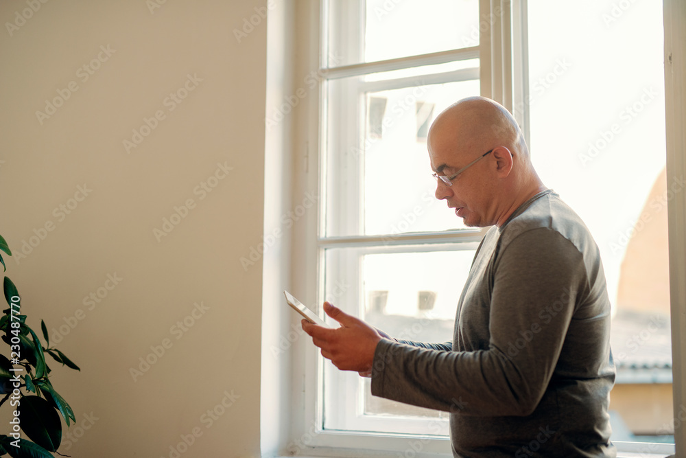 Senior male using a tablet for browsing the internet, happy and smiling