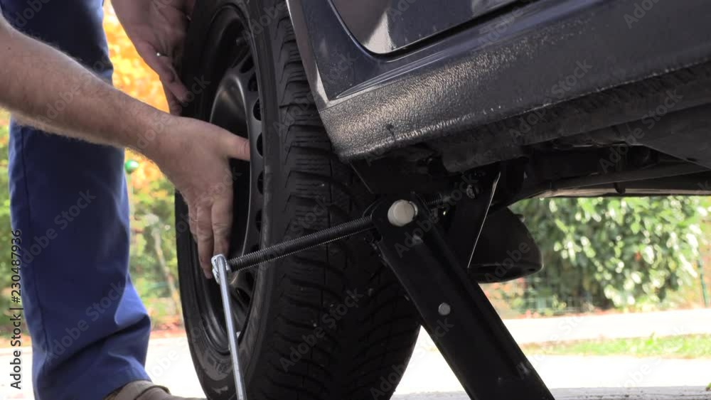 A man in work trousers replaces a car wheel,Slow Motion A man in work trousers replaces a car wheel,Slow Motion