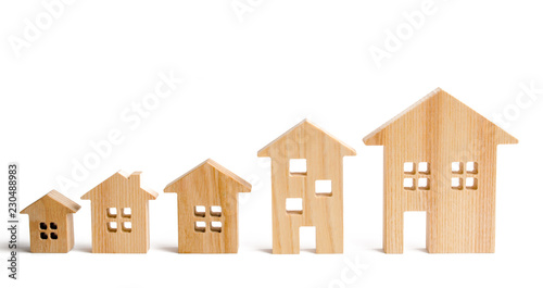 Wooden houses stand in ascending order on a white background. Isolate The concept of increasing population density and high-rise buildings. Agglomeration and urban growth. Selective focus