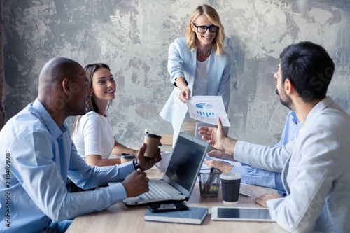 Corporate business team and manager in a meeting. Leader hand out documents to collegaues. photo