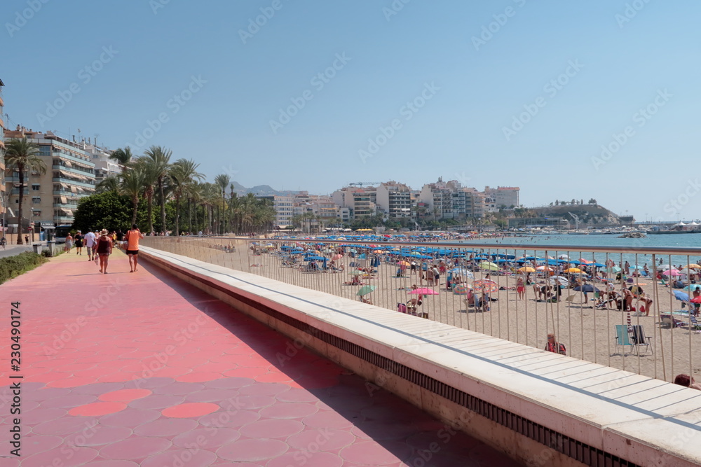 Obraz premium Paseo de la playa de Poniente de Benidorm en España con gente irreconocible paseando, tomando el sol en la arena y bañandose en el agua