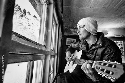 Man playing guitar by window