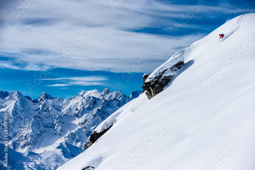 Skier skiing down a snowy steep mountain photo