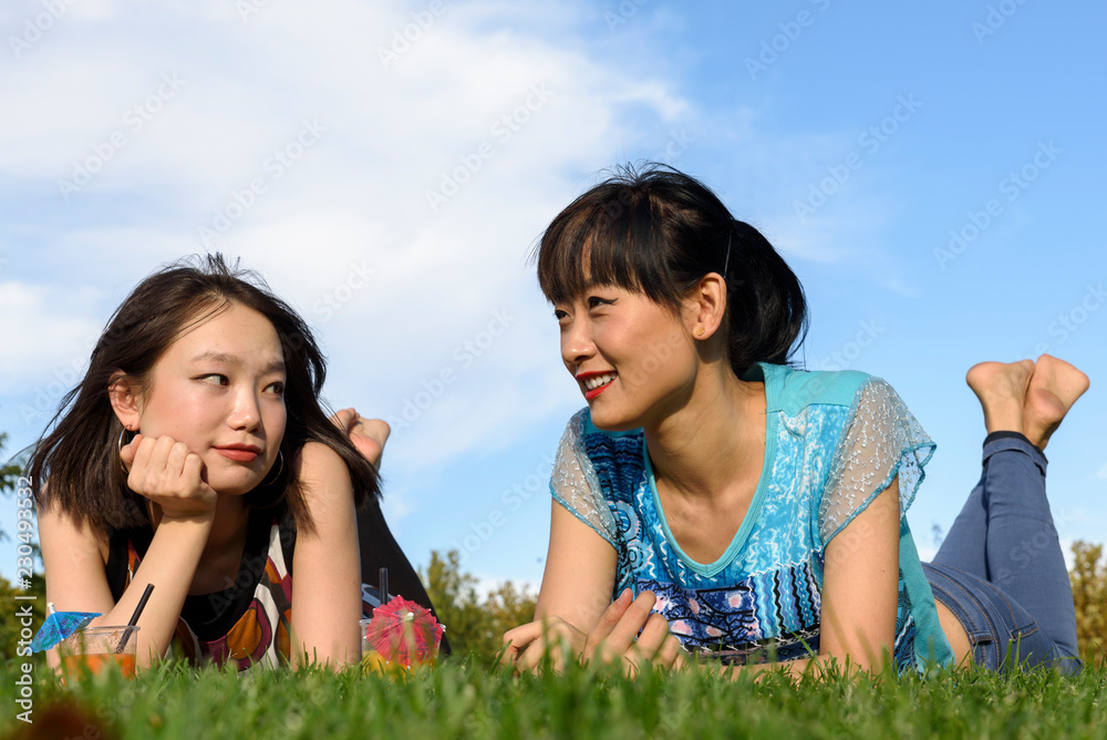 Asian women lying on park grass