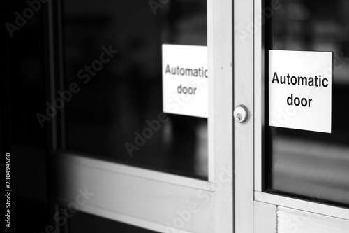 Obraz na plátne Doors of glass and metal with a lock and signs with the words automatic doors
