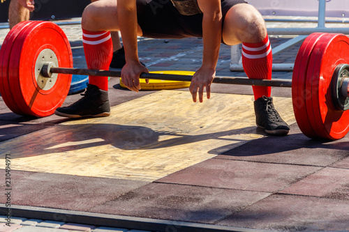 Powerlifter preparing for deadlift of barbell during competition of powerlifting
